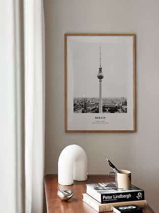 Gerahmtes Schwarz-Weiß-Berlin-Poster über Holztisch mit Büchern, Vase und Tasse