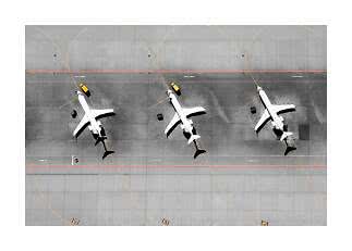 Luftfoto af tre hvide fly parkeret ved gaten på en grå lufthavnsforplads