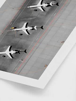 Luftfoto af tre fly parkeret på en grå lufthavnsforplads med markeringer