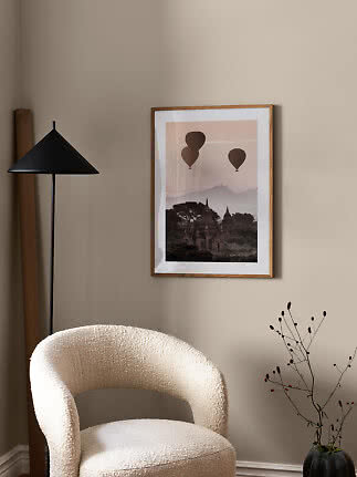 Gerahmtes Poster mit Heißluftballons über Tempeln an einer beigen Wohnzimmerwand.