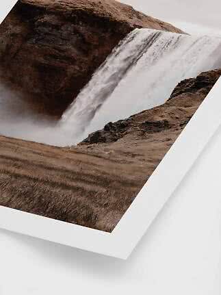Indrammet fotoprint af stort vandfald over mørke klipper i brunt landskab