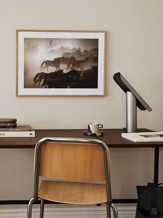 Skrivebord med stol, lampe og indrammet hestefoto på væggen