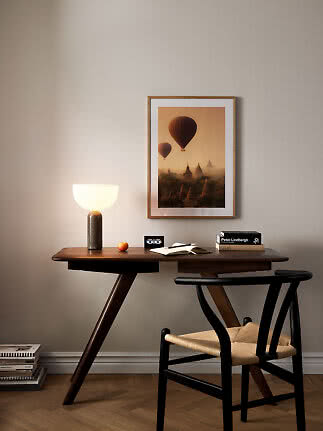 Schreibtisch aus dunklem Holz mit Tischlampe, Stuhl und gerahmtem Heißluftballon-Poster