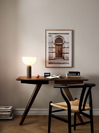 Minimalistischer Schreibtisch aus dunklem Holz mit Stuhl, Lampe und gerahmter Fotokunst