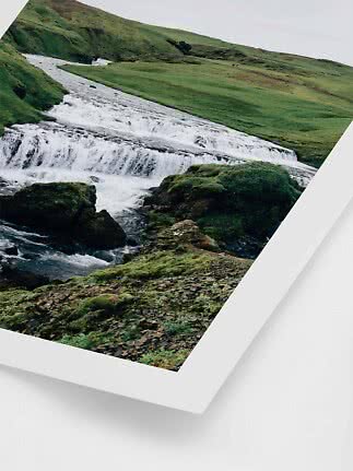 Indrammet foto af et lille vandfald i grønt, kuperet landskab