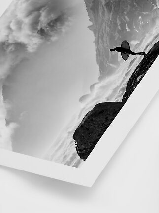 Black-and-white poster of a surfer running along a rocky shore in mist and waves