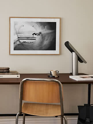 Bureau avec chaise, lampe et photo noir et blanc encadrée d’un surfeur dans un tube au mur