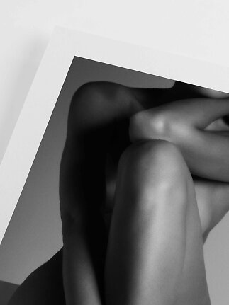 Black-and-white art photo of a seated nude body partly hidden behind a white frame