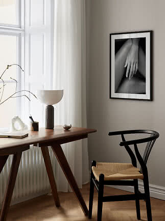 Black framed black-and-white art print of a hand on a wall in a minimalist interior