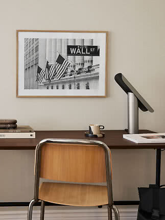 Indrammet sort-hvid Wall Street-plakat over skrivebord med stol og bordlampe