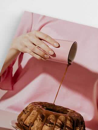 Mano in abito rosa versa salsa al cioccolato su una torta marmorizzata