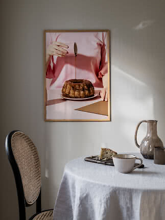 Poster da cucina incorniciato con persona in rosa che versa glassa su una torta ciambella