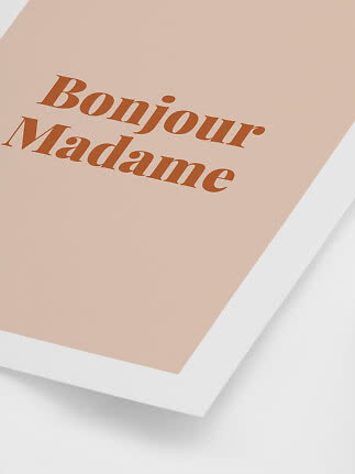 Lyserød plakat med hvid ramme og teksten "Bonjour Madame" i brun skrift