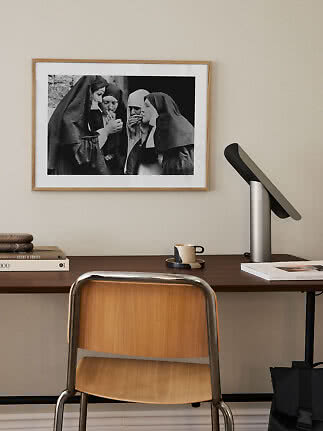 Skrivebord med træstol, lampe og indrammet sort-hvidt foto på væggen