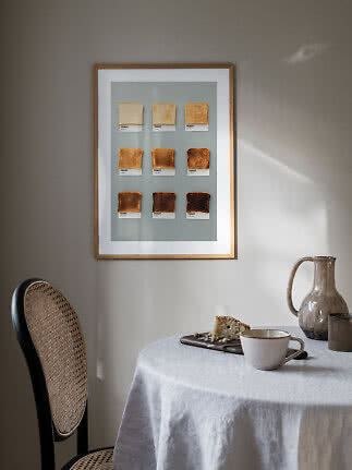 Indrammet plakat med ni skiver toast i forskellige ristningsgrader over et bord med kop og kande