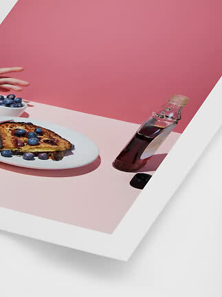 Gerösteter Toast mit Blaubeeren auf einem Teller neben einer Sirupflasche vor rosa Hintergrund