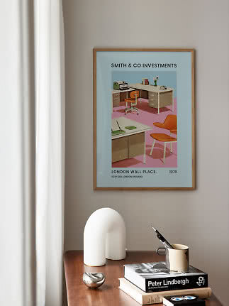 Póster retro enmarcado con escena de oficina sobre una mesa de madera con libros y objetos decorativos