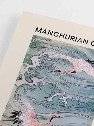 Närbild av konstposter med tranor över blågröna vågor och texten "MANCHURIAN"