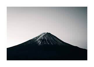 Foto en blanco y negro de una montaña solitaria con cima nevada bajo un cielo vacío