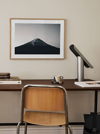 Oficina en casa con silla de madera, lámpara de escritorio y cuadro de montaña en blanco y negro