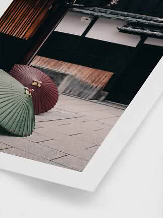 Twee traditionele papieren parasols op een stenen straat voor een houten gebouw.