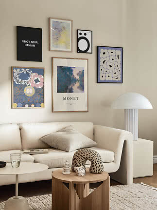 Bright living room with gallery wall above white sofa, round wood table and white lamp