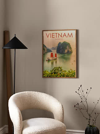 Indrammet Vietnam Halong Bay-plakat på væg over en lys lænestol ved en sort gulvlampe