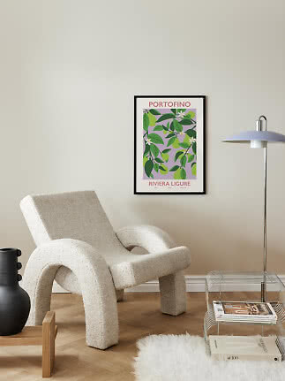 Framed Portofino poster with lemon branches above a cream lounge chair in a modern living room