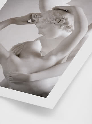 Nærbillede af hvid klassisk skulptur med to sammenflettede figurer i hvid ramme