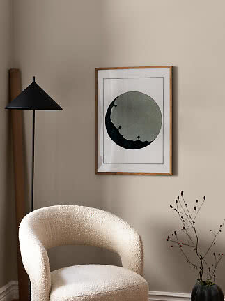Affiche abstraite encadrée en bois avec forme circulaire verte et sombre sur mur beige