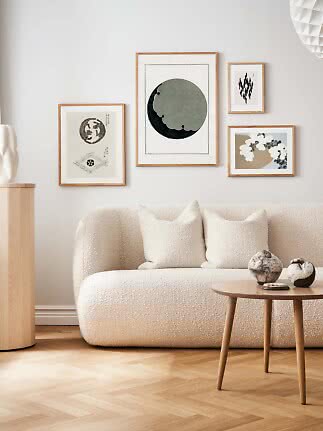Salon avec canapé bouclé crème et quatre affiches d’art encadrées sur mur clair
