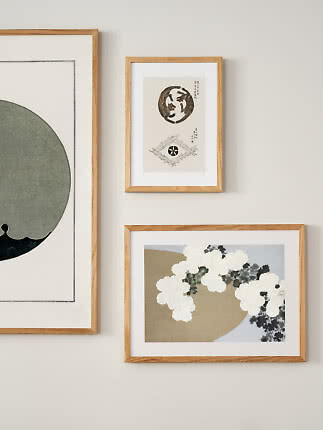Three art prints in light wood frames hanging on a white wall.