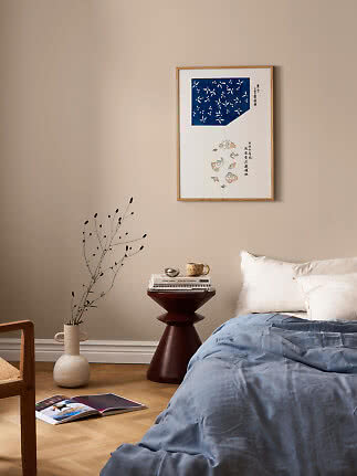 Camera da letto con piumone blu, cuscini bianchi e stampa incorniciata su parete beige