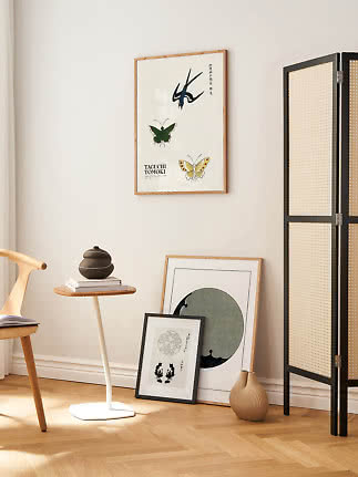 Helles Wohnzimmer mit gerahmtem Kunstposter, Beistelltisch, Vasen und schwarzem Raumteiler