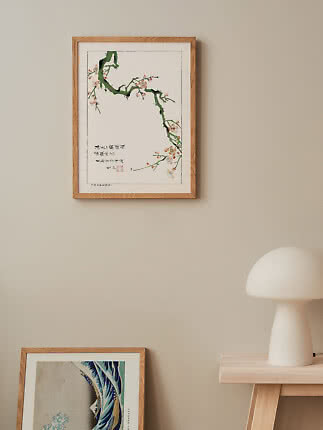 Wood-framed print of a flowering branch with calligraphy on a beige wall