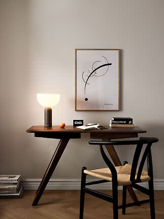 Wooden desk with glowing table lamp, chair, books and abstract wall poster
