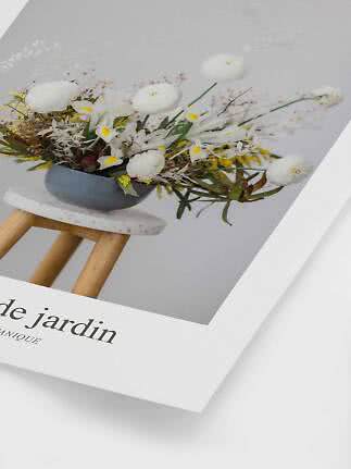 Poster med blomsterarrangemang i grå skål med vita blommor på en liten träpall