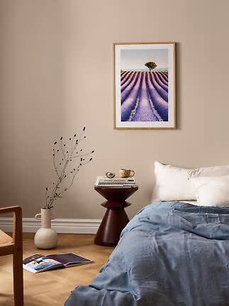 Framed lavender field print above a bed in a bright bedroom
