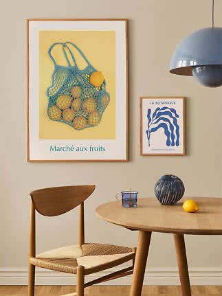 Ingelijste poster met blauwe nettas vol citroenen op gele achtergrond in een stijlvolle eethoek
