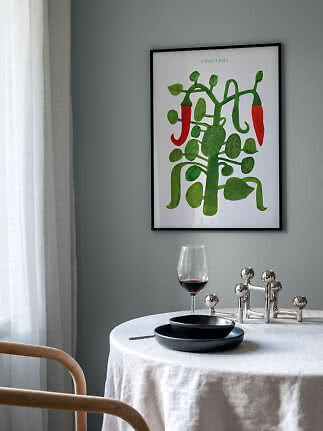 Póster enmarcado de planta de chile verde con chiles rojos en pared gris sobre una mesa