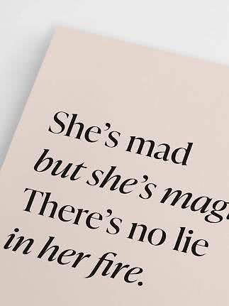 Nærbillede af beige plakat med sort typografi og engelsk citat.