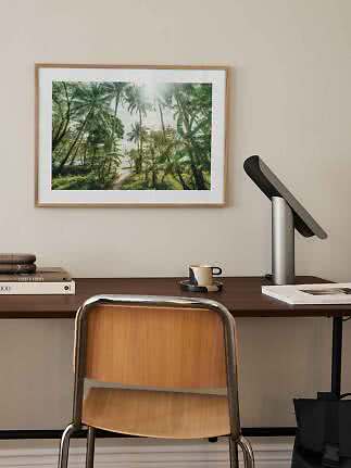 Gerahmter Palmenprint über Schreibtisch mit Stuhl, Lampe, Tasse und Büchern
