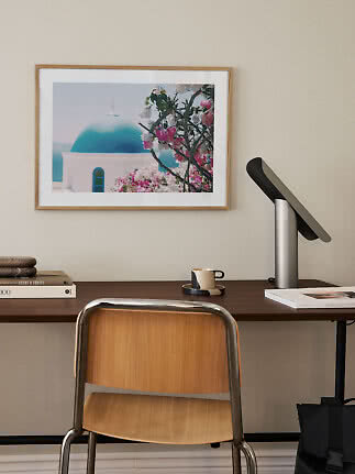 Desk with wooden chair, black lamp, and framed photo of a blue dome with pink flowers