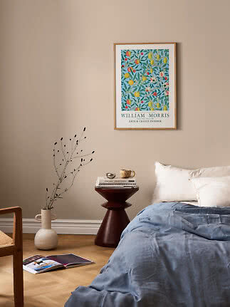 Indrammet William Morris-plakat med farverigt blomstermønster over seng i beige soveværelse