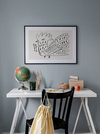 Desk with globe and chair beneath framed black-and-white bird illustration