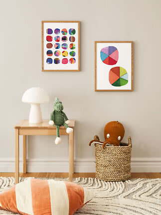 Habitación infantil con láminas enmarcadas coloridas, lámpara de mesa, peluche verde y cesta con pulpo.