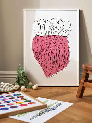 Vit inramad poster med enkel rosa jordgubbsillustration, lutad mot väggen på golvet