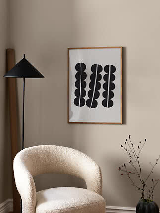 Minimalistisches Wohnzimmer mit cremefarbenem Sessel, schwarzer Stehlampe und gerahmtem Grafikposter