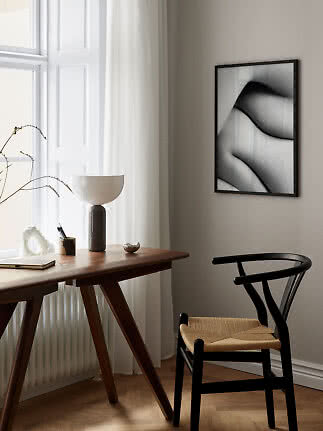 Black framed abstract poster on beige wall above desk and black chair