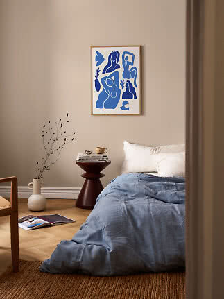 Bedroom with blue bedding and framed blue abstract art on a beige wall